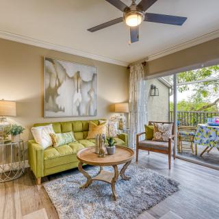 A cozy living room featuring a green sofa, abstract artwork, and a balcony view.