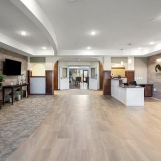 A spacious and modern lobby area featuring a reception desk, kitchenette, and contemporary lighting.