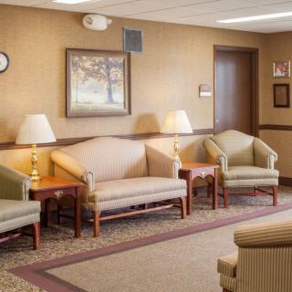 A cozy waiting room with sofas, chairs, and lamps.