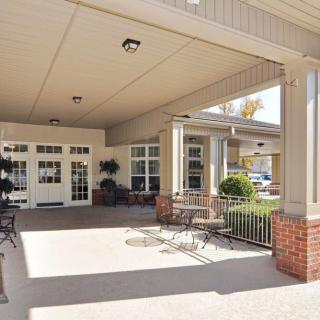 A covered entrance with outdoor seating and large windows.
