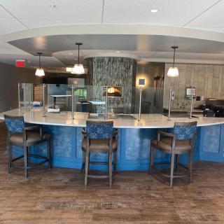 A modern bar area with a curved counter, stylish chairs, and elegant lighting fixtures.