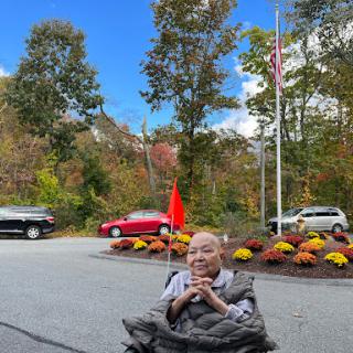 A moment captured in the beauty of autumn, featuring a person in a wheelchair surrounded by vibrant fall colors and flags.