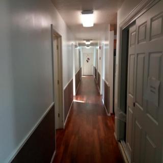 A long indoor hallway with multiple doors and wooden flooring.
