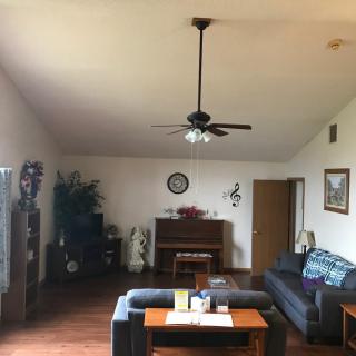 A cozy living room with a sofa, piano, and ceiling fan.