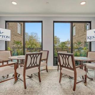 A well-lit dining area with multiple seating arrangements and large windows providing an outdoor view.