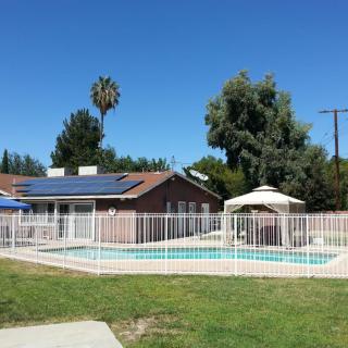 A house with solar panels and a fenced swimming pool in the backyard on a sunny day.