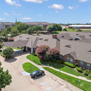 Aerial view of a residential building with a parking lot and landscaped surroundings.