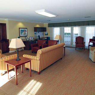 A spacious and well-furnished living room with sofas, lamps, and large windows.