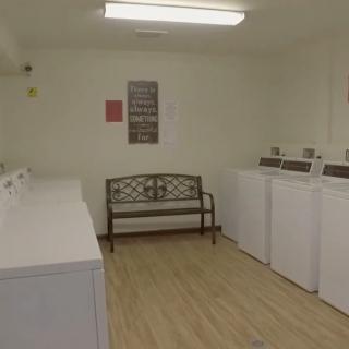 A small laundry room with several washing machines and a bench.