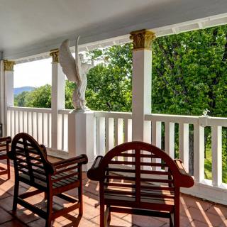 A peaceful porch with chairs overlooking a scenic green landscape.