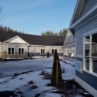 A residential building surrounded by snow under a clear blue sky.