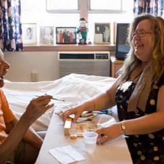 A caregiver assisting an elderly person in a nursing home setting.