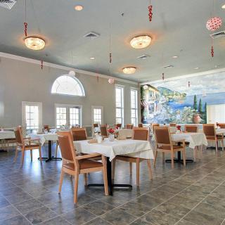 A spacious restaurant dining area with elegantly set tables and a large mural on the wall.
