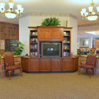 A cozy living room with a wooden TV stand, bookshelves, and comfortable chairs.