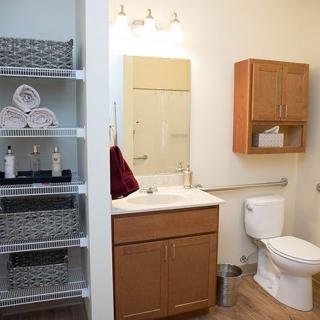 A neatly organized bathroom with shelves, a sink, mirror, and wooden cabinets.