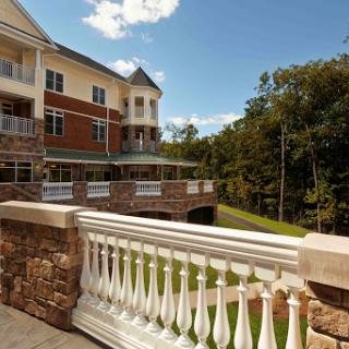 A picturesque view of a modern residential building with a balcony overlooking landscaped greenery.