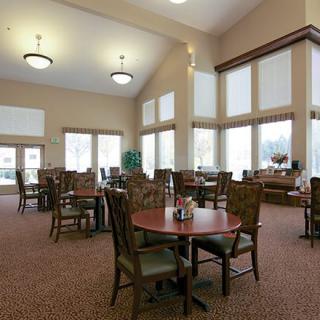 A spacious and well-lit dining area with multiple tables and chairs, featuring large windows.