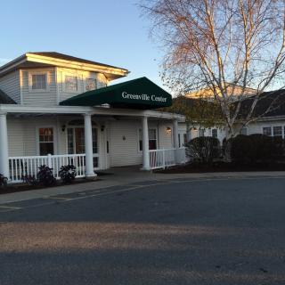 Entrance of a building with an awning surrounded by trees at sunset.