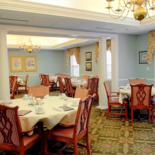 A traditional dining room with elegantly set tables and chandeliers.
