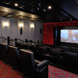 A small, modern movie theater with comfortable seating and a large screen.
