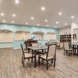 A cozy dining area with neatly arranged tables and chairs under warm lighting.