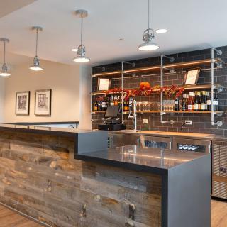A modern, rustic bar interior with pendant lighting and stocked shelves.
