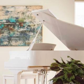 A modern living room featuring a white grand piano and abstract artwork.