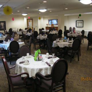 A dining room setup with multiple tables and chairs, ready for guests.