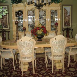 Elegant dining room with a large table, upholstered chairs, and a decorative cabinet.