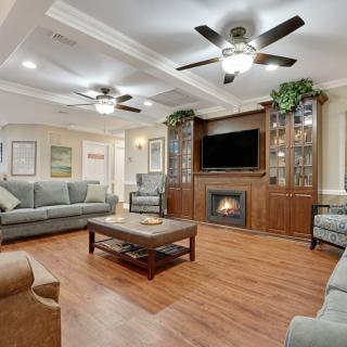 A spacious living room with a modern interior, featuring comfortable seating, a wooden floor, and a fireplace beneath a mounted television.