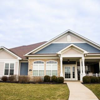 A suburban residential house with a well-maintained lawn and blue siding.