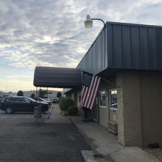 A storefront with an American flag hanging, under a cloudy sky.