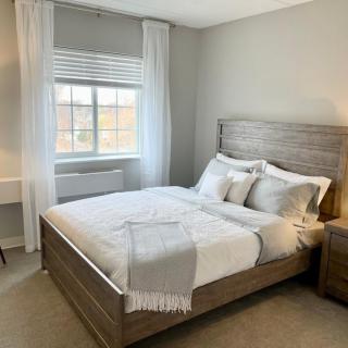 A modern and minimalist bedroom featuring neutral tones and wooden furniture.