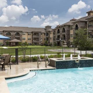A modern apartment complex with a swimming pool and landscaped outdoor area.