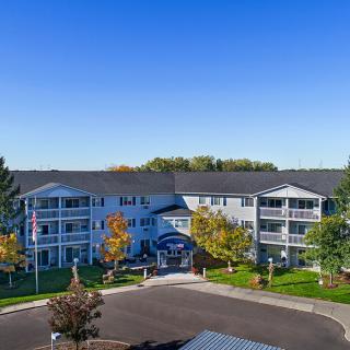 A residential apartment building surrounded by trees under a clear blue sky.