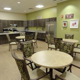 A modern kitchen and dining area featuring wooden tables and stylish chairs, set against a vibrant green wall.