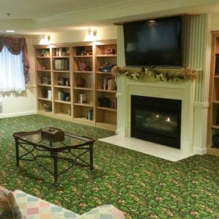 A cozy living room with a fireplace, wall-mounted television, and built-in bookshelves.