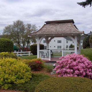 A tranquil garden scene featuring a gazebo surrounded by vibrant flowers and greenery.