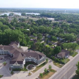 An aerial view showcasing a lush residential area with homes nestled among trees and a nearby road.