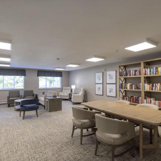 A modern library reading room with bookshelves, tables, and comfortable seating.