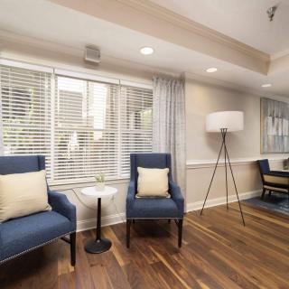 A cozy living room with blue chairs and a floor lamp on hardwood flooring.