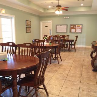 A cozy dining room with multiple tables and chairs, featuring a ceiling fan and tiled flooring.