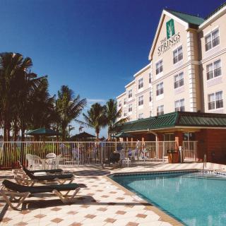A sunny day at a hotel with a swimming pool and palm trees.
