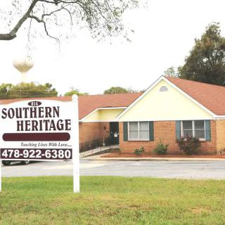 A real estate office with a prominent sign for Southern Heritage located in front of the building on a grassy lawn.