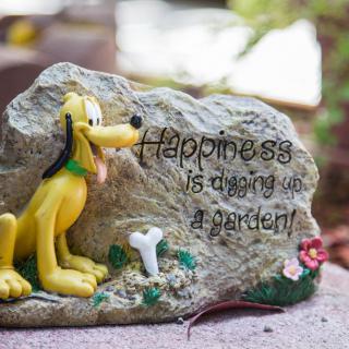 Decorative garden stone with a dog figure and 'Happiness is digging up a garden!' quote.