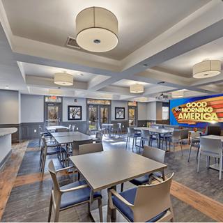 A modern dining area with neatly arranged tables and chairs, featuring ceiling lights and contemporary decor.