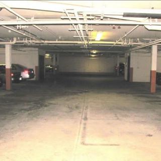 An underground parking garage with dim lighting and parked cars.