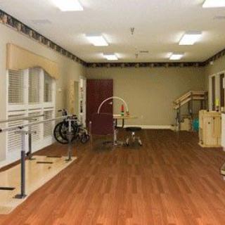 A well-equipped rehabilitation room with exercise equipment and wooden flooring.