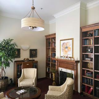 A cozy reading nook featuring comfortable chairs, bookshelves filled with books, and a decorative plant.
