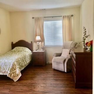 Cozy bedroom with a single bed, nightstand lamp, and comfortable seating.
